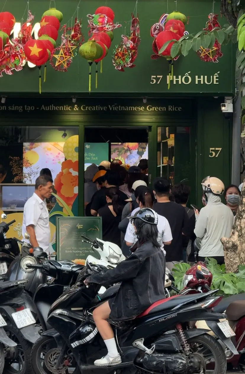 Customers queuing outside the green shop at 57 Phố Huế under red lanterns, motorbikes parked in front.