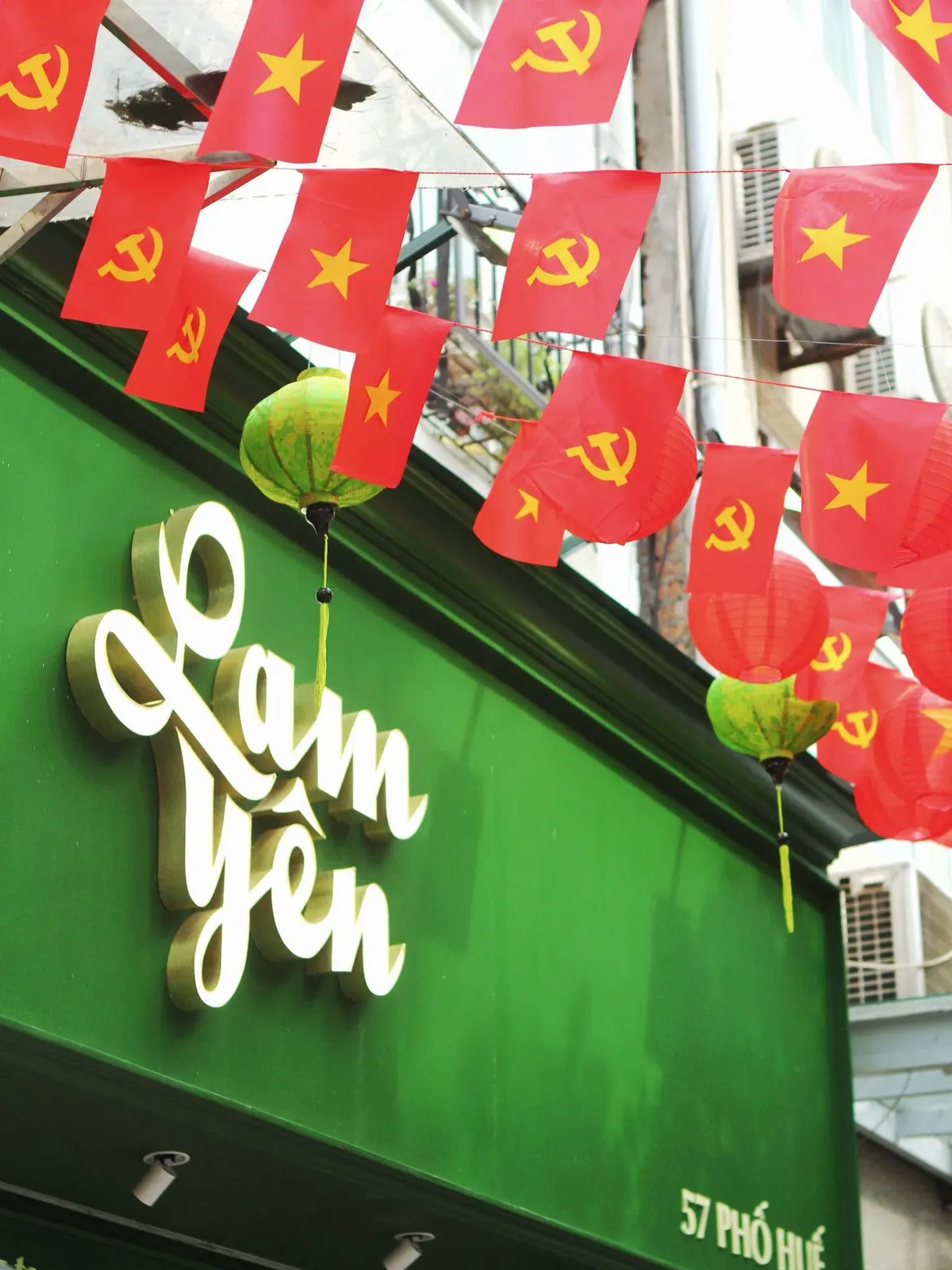 The white “Lam Yên” sign on the green shop front, under strings of red flags.