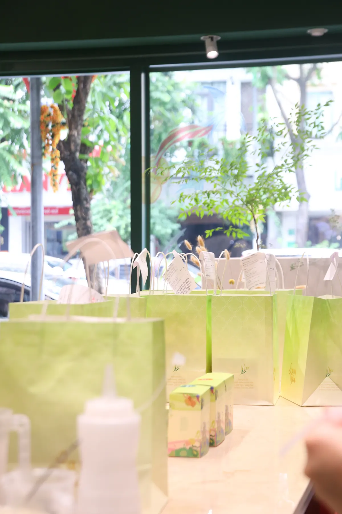 Pale green paper bags lined up on a counter beside the shop window.