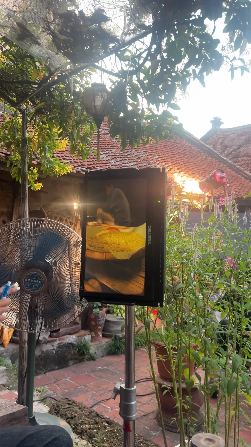 A tablet on a stand showing a mooncake picture, in a courtyard garden under a tree.